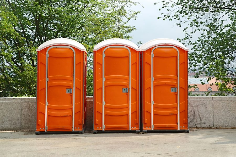 Row of orange portable toilets delivered for a Weston area job