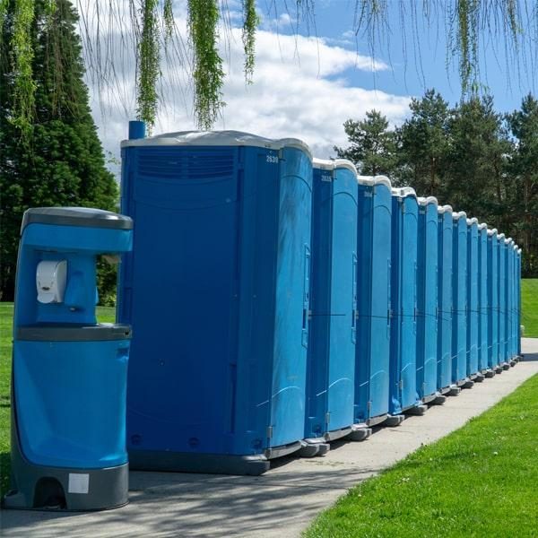 Portable freshwater handwashing station beside a row of portable toilets